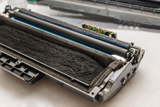 the cartridge from the laser printer, filled with toner, paint, with a chip, lies disassembled on a white table