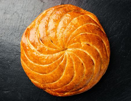 Epiphany cake or galette des rois in French on black slate background