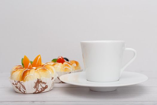 Selective focus, close up of white ceramic coffee cup on saucer with two tea cakes next to it