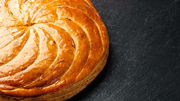 Epiphany cake or galette des rois in French on black slate background