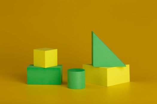Yellow and green geometric figures against dark yellow background. Minimalistic concept for advertising or banner