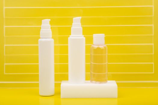 White unbranded skin care products on bright yellow background with stripes. Face cream, cleaning foam and lotion. Creative concept of daily, summer or anti aging skin care