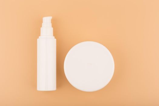 Minimalistic flat lay with face and body cream in white jars on beige background. 