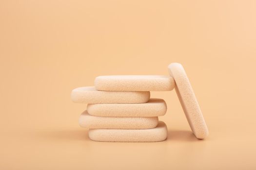 Still life with stack of make up sponges on beige background.Concept of make up artistry and visage