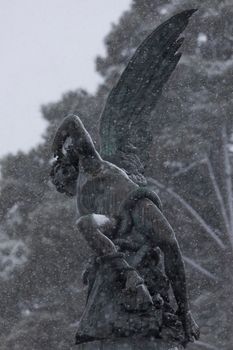 Madrid, Spain - January 07, 2021: A detail of the famous bronze sculpture of the Angel Caido fountain, in the Buen Retiro park in Madrid, on a snowy day, and a wave of polar cold.