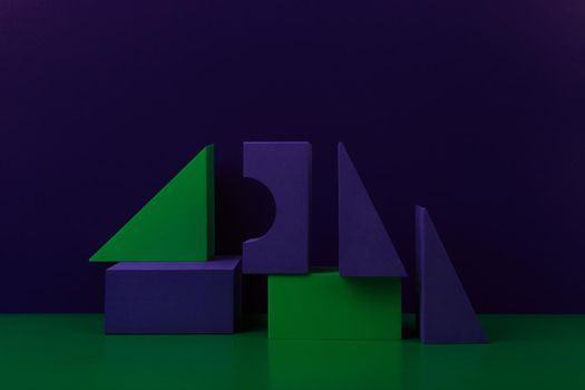 Duotone geometric composition with green and purple figures on green table against purple background