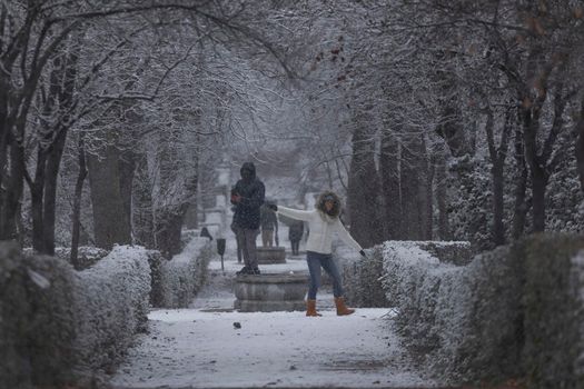 Madrid, Spain - January 07, 2021: People enjoying a walk through the Buen Retiro park in Madrid, in the middle of a snowy day, due to a wave of polar cold.