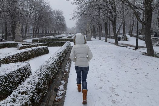 Madrid, Spain - January 07, 2021: A young girl enjoys a walk through the Buen Retiro park in Madrid, in the middle of a snowy day, due to a wave of polar cold.
