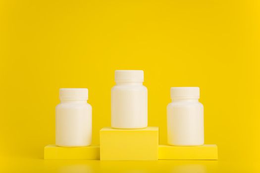 Three white unbranded medication bottles on yellow winner pedestal against yellow background with space for text. 