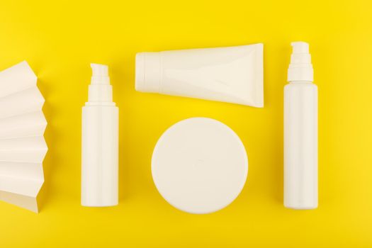 Bright yellow flat lay with set of cosmetic products for skin and body care on yellow background.Concept of daily skin and body care or summer treatment