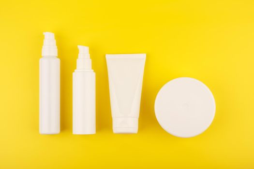Body and face creams in a row on bright yellow background. Concept of skin and body care and wellbeing