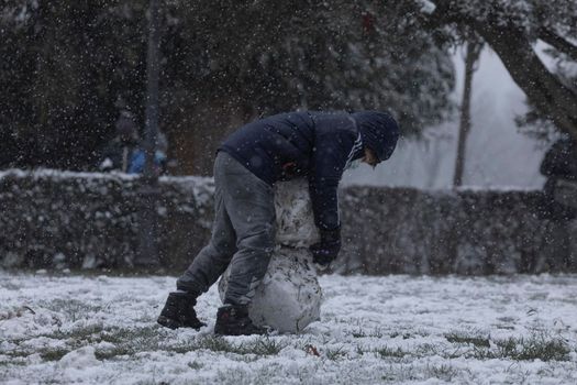 Madrid, Spain - January 07, 2021: Children playing with snow and making snowmen, in the Buen Retiro park in Madrid, in the middle of a snowy day, due to a wave of polar cold.