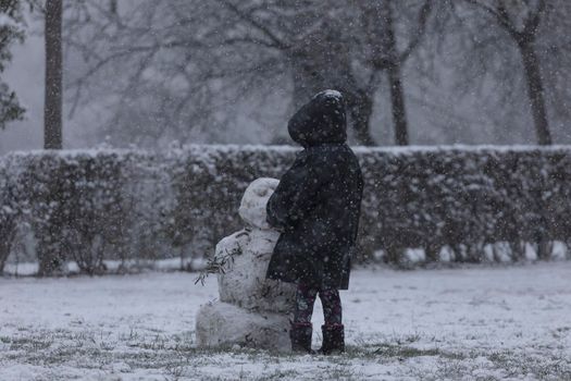 Madrid, Spain - January 07, 2021: Children playing with snow and making snowmen, in the Buen Retiro park in Madrid, in the middle of a snowy day, due to a wave of polar cold.