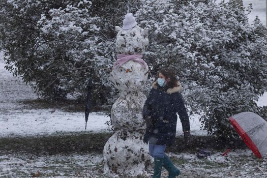 Madrid, Spain - January 07, 2021: Children playing with snow and making snowmen, in the Buen Retiro park in Madrid, in the middle of a snowy day, due to a wave of polar cold.