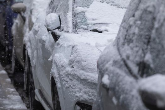 Madrid, Spain - January 07, 2021: Cars parked in a Madrid street, covered with snow, by a wave of polar cold, in the middle of the blizzard and snow.