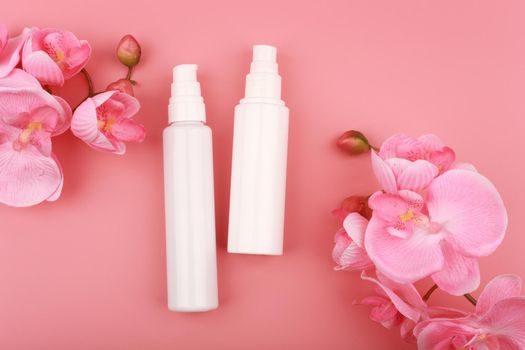 Flat lay with two creams on pink background with flowers. Concept of skin care and beauty or daily skin routine