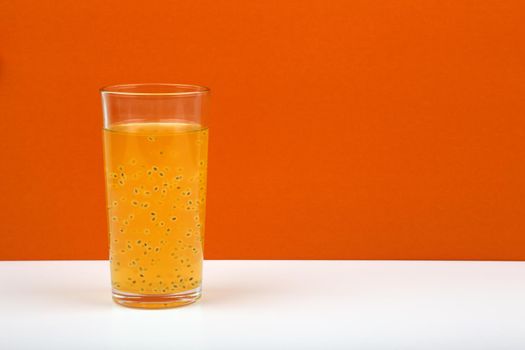 Creative minimalistic still life with fresh fruit juice in transparent glass on orange background with space for text. The concept of healthy lifestyle, wellbeing or detox