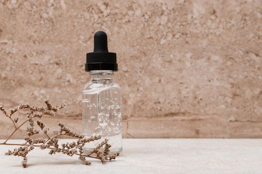 Skin serum in transparent bottle with black cap against marble background. Concept of skin care and anti aging treatment