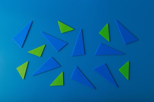 Minimalistic abstract flat lay with green and blue triangles on blue background. High quality photo