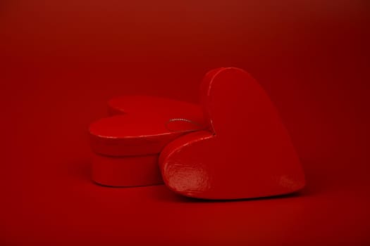 Still life with two glossy heart shaped gift boxes on red background. The concept of Valentine's day and love