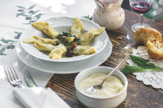 Delicious italian fresh Casoncelli served on rustic wooden table with homemade bread and red wine. Casoncelli alla Bergamasca. Typical italian restaurant. Fresh cooked homemade pasta.