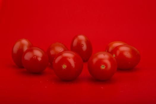 Still life with tomatoes with drops of water on red background. High quality photo