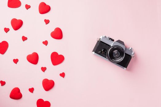 Valentines' day background. Vintage retro camera and red hearts composition greeting card love Valentines day I love photography concept on pink background with copy space. Top View from above