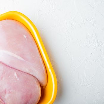 Fresh chicken breast meat in open tray, on white background with copy space for text