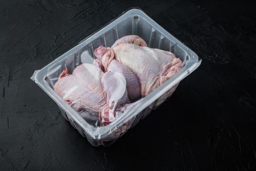 Raw chicken in plastic sealed plastic box, on black background with copy space for text
