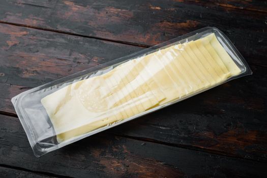 Cheddar cheese in vacuum pack, on dark wooden background