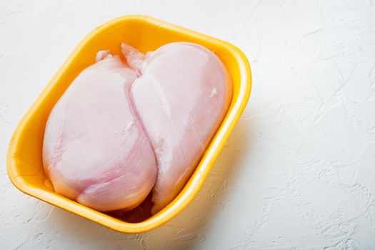 Raw chicken breast fillets in tray, on white background