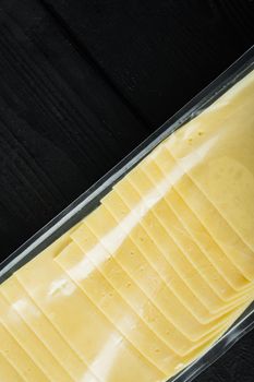 Cheddar cheese in vacuum pack, on black wooden table with copy space for text