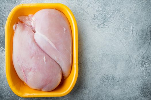 Raw chicken breast fillets in tray, on gray background with copy space for text
