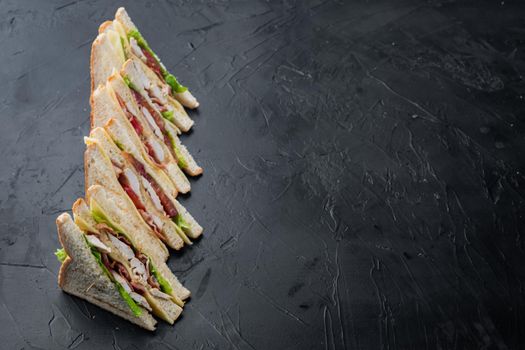 Club sandwich with meat, cheese tomato, ham, on black background with copy space for text