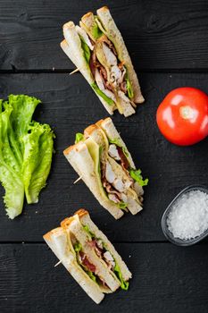 Homemade chicken sandwich halves, on black wooden background, top view
