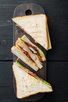 Fresh sandwiches with ingredient, on black wooden background, top view