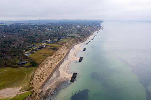 Vejby, Denmark - January 1, 2021: Aerial drone view of the coastline with breakwaters at Vejby Beach.