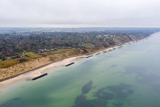 Vejby, Denmark - January 1, 2021: Aerial drone view of the coastline with breakwaters at Vejby Beach.