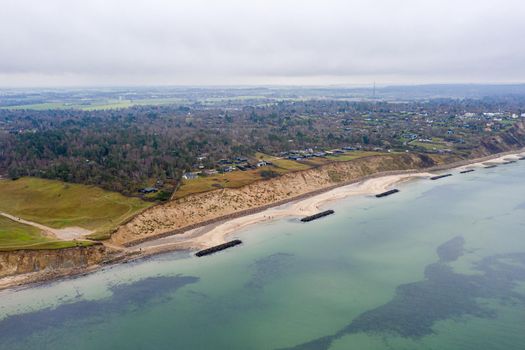 Vejby, Denmark - January 1, 2021: Aerial drone view of the coastline with breakwaters at Vejby Beach.