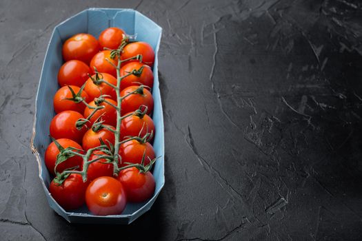 Red small cherry tomatoes, on black background with copy space for text