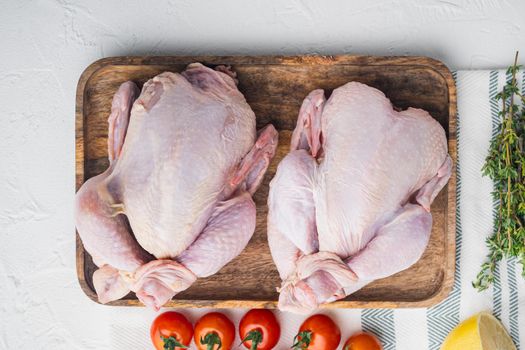Organic whole fresh poussins with herbs and ingredients, on white background, top view with copy space for text