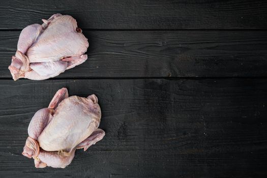 Raw small young whole chicken, on black wooden background, top view with copy space for text