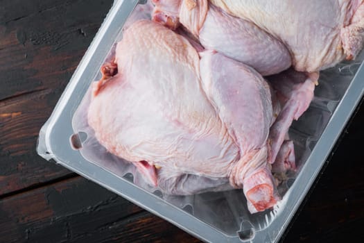 Raw chicken set in plastic vacuum tray, on old wooden table, top view