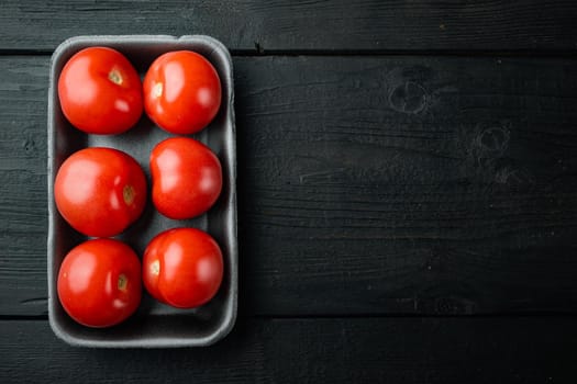 Fresh red organic tomatoes, on black wooden table with copy space for text