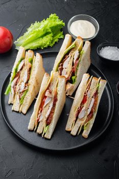 Halves of fresh club sandwiches, on black background