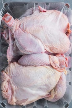 Plastic container with raw chicken set, on black wooden table, top view