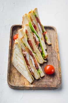 Homemade club sandwich made with turkey, bacon, ham, tomatoes, on white background
