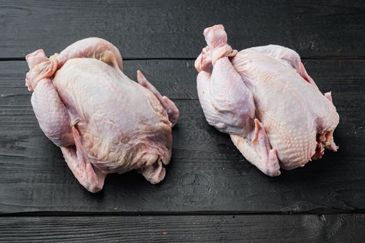 Raw coquelet chickens meat, on black wooden background