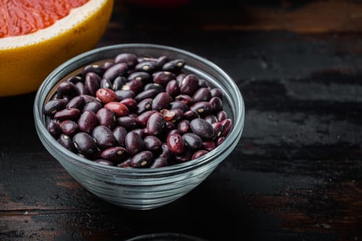 Red beans in bowl with healthy ingredients on dark wooden background, with space for text.