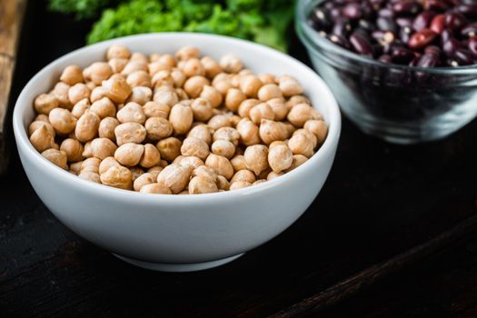 Chickpea in white bowl on dark wooden background.